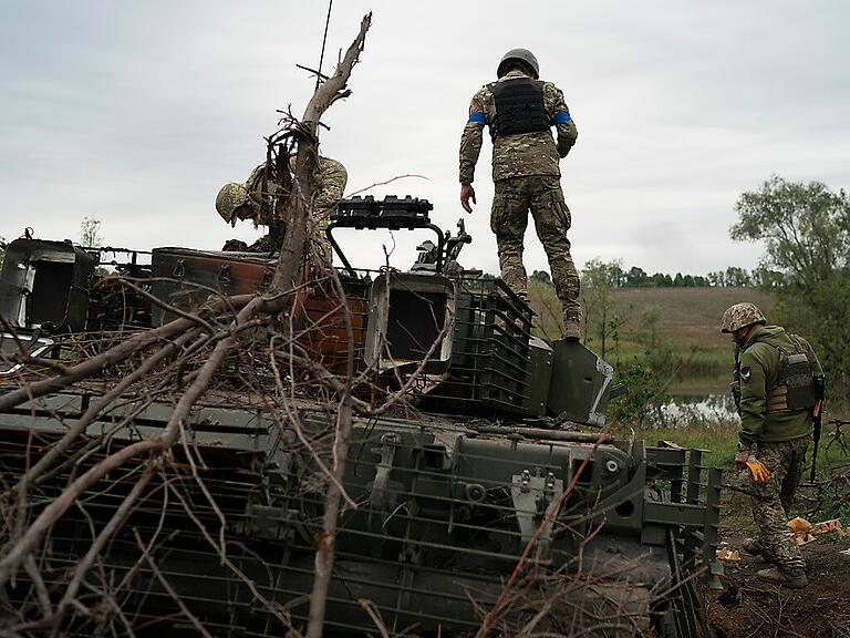 Ukrainische Soldaten stehen auf einem zerstörten russischen Panzer in einem zurückeroberten Gebiet nahe der Grenze zu Russland in der Region Charkiw. Foto: Leo Correa/AP/dpa