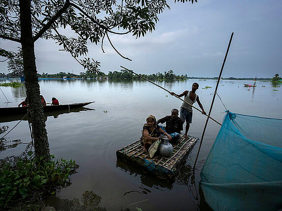 Von der Überschwemmung betroffene Menschen erreichen mit einem Behelfsboot ein sichereres und höher gelegenes Gebiet im Dorf Tarabari. Foto: Anupam Nath/AP/dpa