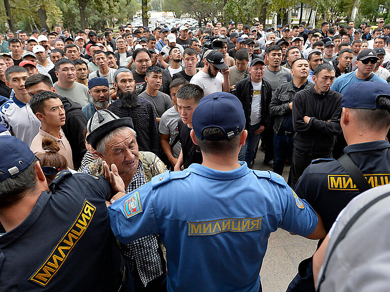 Polizisten drängen in der kirgisischen Hauptstadt Bishkek Freiwillige zurück, die sich vor dem Regierungsgebäude versammeln und ihre Entsendung in die Konfliktzone an der kirgisisch-tadschikischen Grenze fordern. Foto: Vladimir Voronin/AP/dpa
