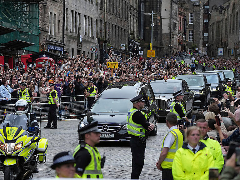 Der Leichenwagen mit dem Sarg von Königin Elizabeth II., der mit der königlichen Standarte von Schottland behängt ist, fährt auf der Royal Mile. Foto: Jon Super/AP/dpa