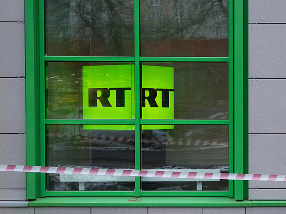 ARCHIV - Das Logo des staatlichen russischen TV-Senders «Russia Today» (RT) ist im Fenster des Firmenbüros in Moskau zu sehen. Der russische Botschafter in Berlin, Sergej Netschajew, hat eine Reaktion auf die Einschränkungen für den russischen Staatssender RT in Deutschland angekündigt. Foto: Pavel Golovkin/AP/dpa
