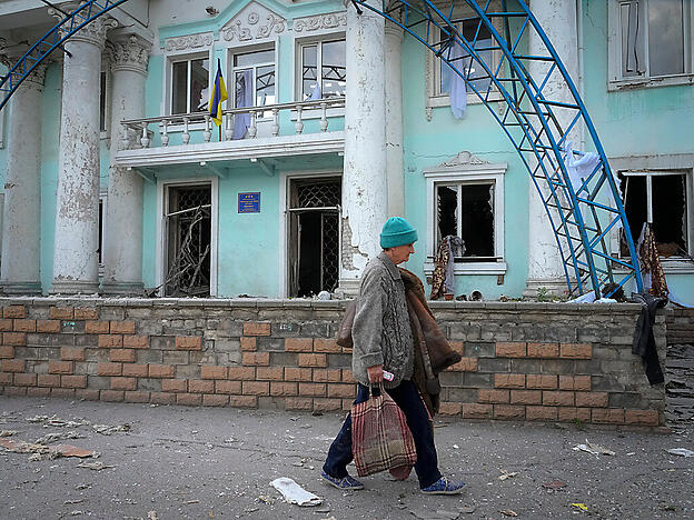 Eine Frau geht in der Nähe eines bei einem russischen Luftangriff zerstörten Gebäudes in Lyssytschansk vorbei. Foto: Efrem Lukatsky/AP/dpa