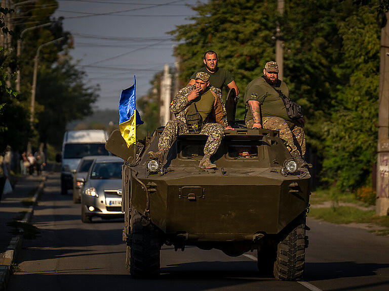 Soldaten der ukrainischen Armee sitzen auf einem gepanzerten Militärfahrzeug.) Foto: Emilio Morenatti/AP/dpa