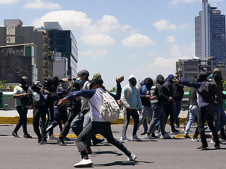 Demonstranten werfen Steine auf die Polizei während einer Demonstration vor der mexikanischen Generalstaatsanwaltschaft. Foto: Fernando Llano/AP/dpa
