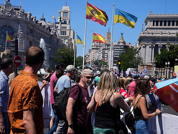 Demonstranten marschieren während einer Anti-Nato-Demonstration an spanischen und ukrainischen Flaggen vorbei. Mehrere Tausend Menschen haben am Sonntag gegen den bevorstehenden Nato-Gipfel in Madrid demonstriert. Foto: Paul White/AP/dpa