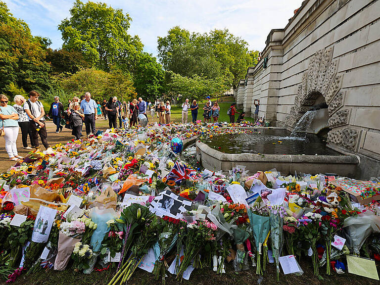 Zahlreiche Blumen und Trauerbekundungen liegen an einem Brunnen im St. James's Park nahe dem Buckingham-Palast. Die britische Königin Elizabeth II. ist am 08.09.2022 im Alter von 96 Jahren gestorben. Foto: Christian Charisius/dpa